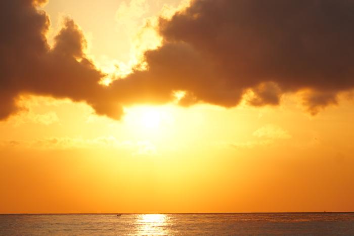 sun breaking under clouds over sea